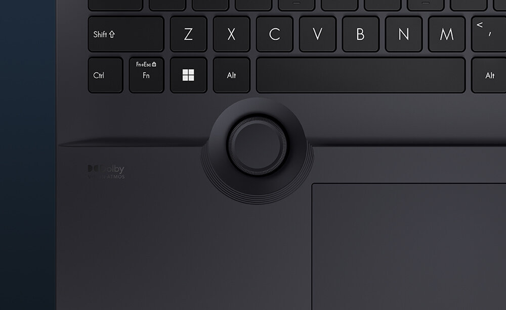  Kołko kontrolne ASUS Dial w rogu touchpada laptopa ProArt StudioBook z koncentrycznymi pierścieniami i widoczną aplikacją Pantone Digital Color na ekranie w tle - intuicyjny fizyczny sterownik ASUS Dial 