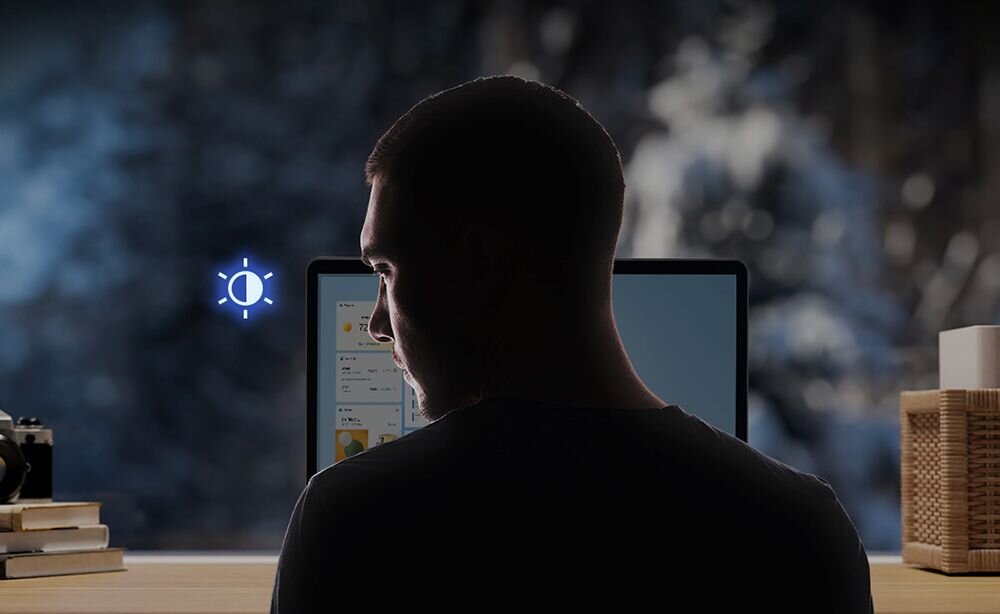 Mężczyzna w ciemnej koszuli pracujący na laptopie ASUS ProArt StudioBook z niebieskimi liniami emanującymi z ekranu symbolizującymi czujnik obecności i śledzenie wzroku - Czujnik obecności