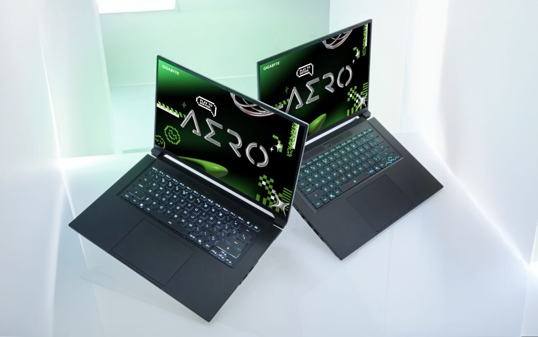 Dwa laptopy GIGABYTE AERO ustawione pod kątem prezentują smukły design i podświetlaną klawiaturę w studiu kreatywnym.     