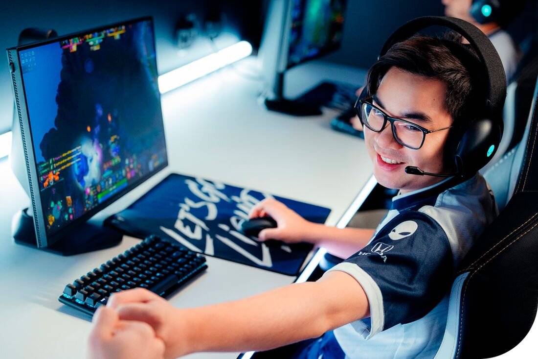 Gamer w słuchawkach i okularach grający na komputerze z laptopem Dell Alienware w niebieskim oświetleniu - Komunikacja głośniki stereo oraz dwa mikrofony z redukcją szumów