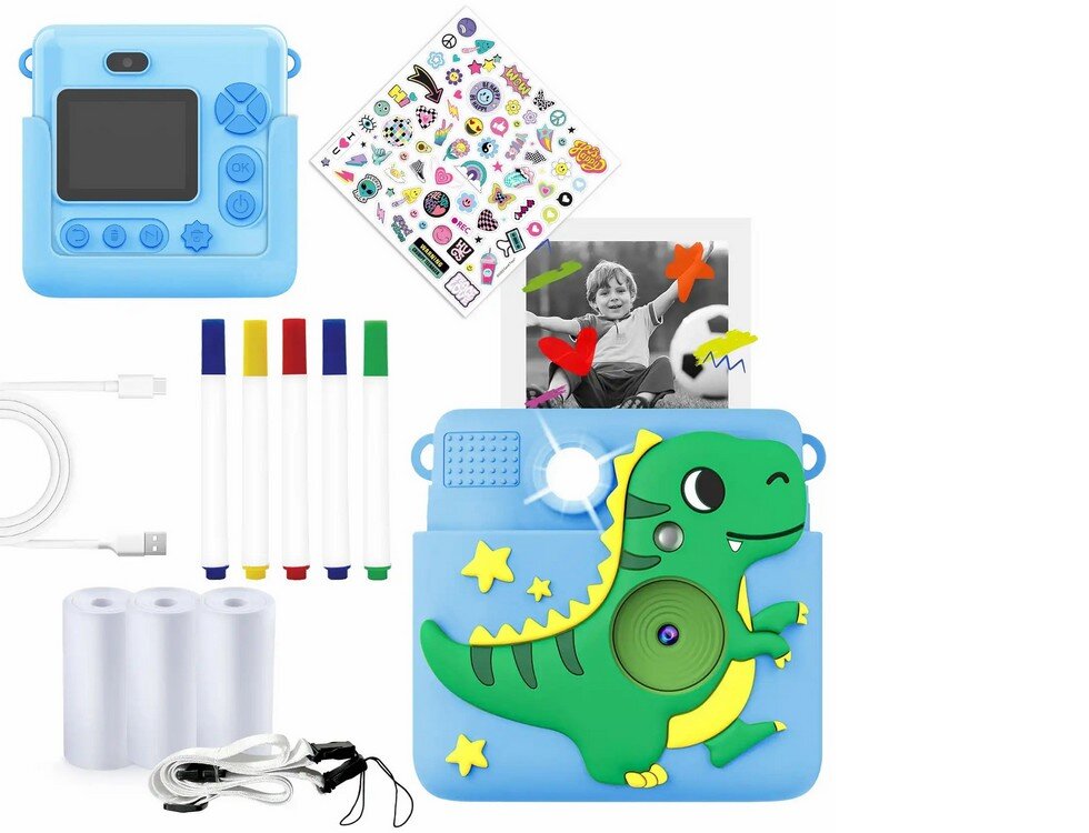 Na obrazie znajduje się niebieski aparat natychmiastowy z motywem dinozaura, zestaw naklejek, kolorowe pisaki, kabel USB, trzy rolki papieru oraz czarno-białe zdjęcie dziecka z piłką. Aparat ma ekran i przyciski na obudowie.