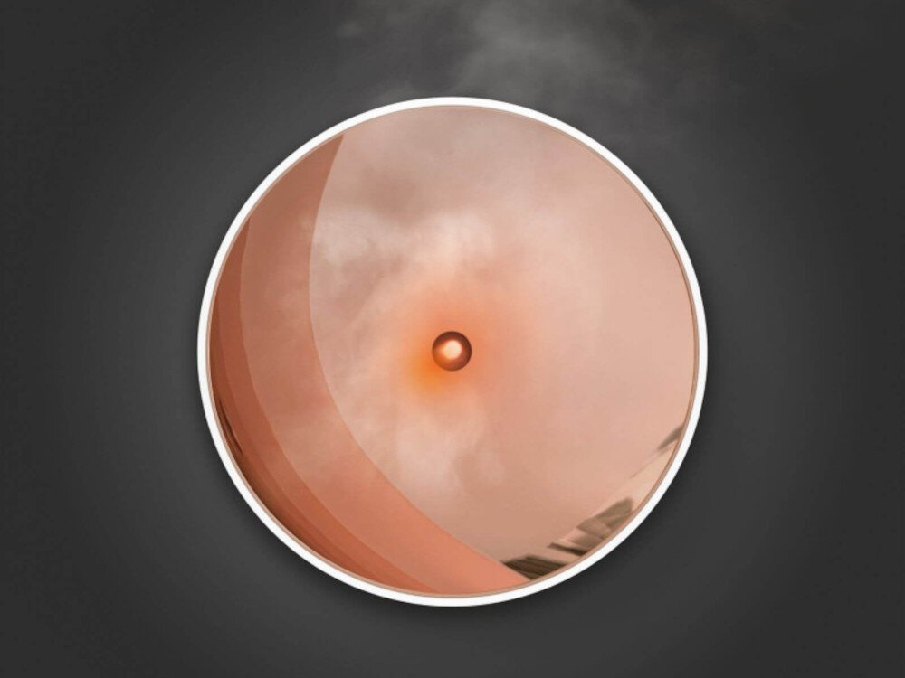 Obraz przedstawia okrągły element z centralnym otworem, z którego wydobywa się delikatna mgiełka. Tło jest ciemne, co podkreśla jasny kolor elementu.