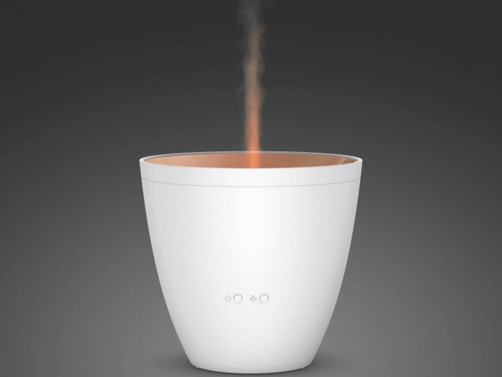 Biały aromatyzer o prostym, nowoczesnym designie emituje delikatną mgiełkę. Na jego powierzchni widoczne są trzy ikony: włącznik, kropka i symbol fali.