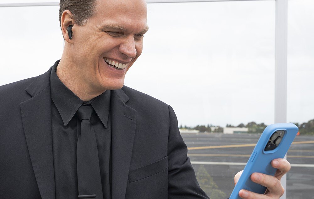 Słuchawki dokanałowe JLAB Jbuds Pods ANC, True Wireless, Bluetooth, szybkie parowanie, osoba trzymająca smartfona w ręku z założonymi słuchawkami