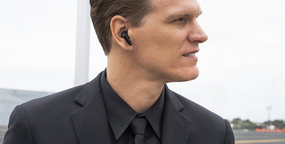 Słuchawki dokanałowe JLAB Jbuds Pods ANC, wodoodporność IP55, odporność na pył i wodę, osoba z założonymi słuchawkami w garniturze