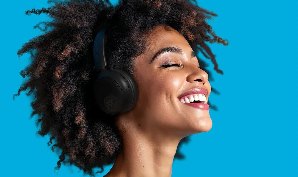 Słuchawki JLAB Headest STUDIO 2 składana konstrukcja mobilność podróż, osoba z założonymi słuchawkami na niebieskim tle