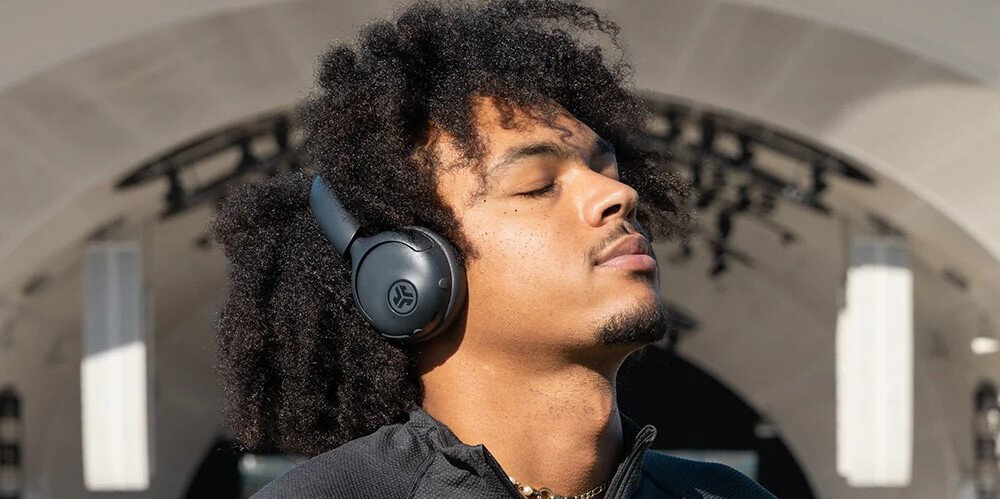Słuchawki nauszne JLAB GO LUX ANC do codziennego użytku, wygoda, aktywna redukcja szumów, bezprzewodowe Bluetooth, osoba z założonymi słuchawkami na głowie na świeżym powietrzu