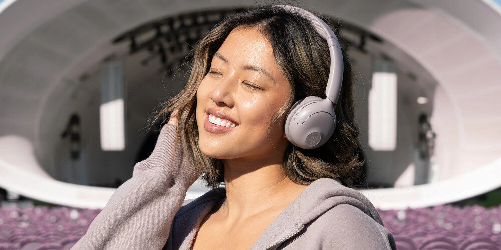 Słuchawki nauszne JLAB GO LUX ANC pasmo 20-20000 Hz dynamika 104 dB membrany dynamiczne szczegółowy dźwięk, osoba z założonymi słuchawkami na głowie na świeżym powietrzu