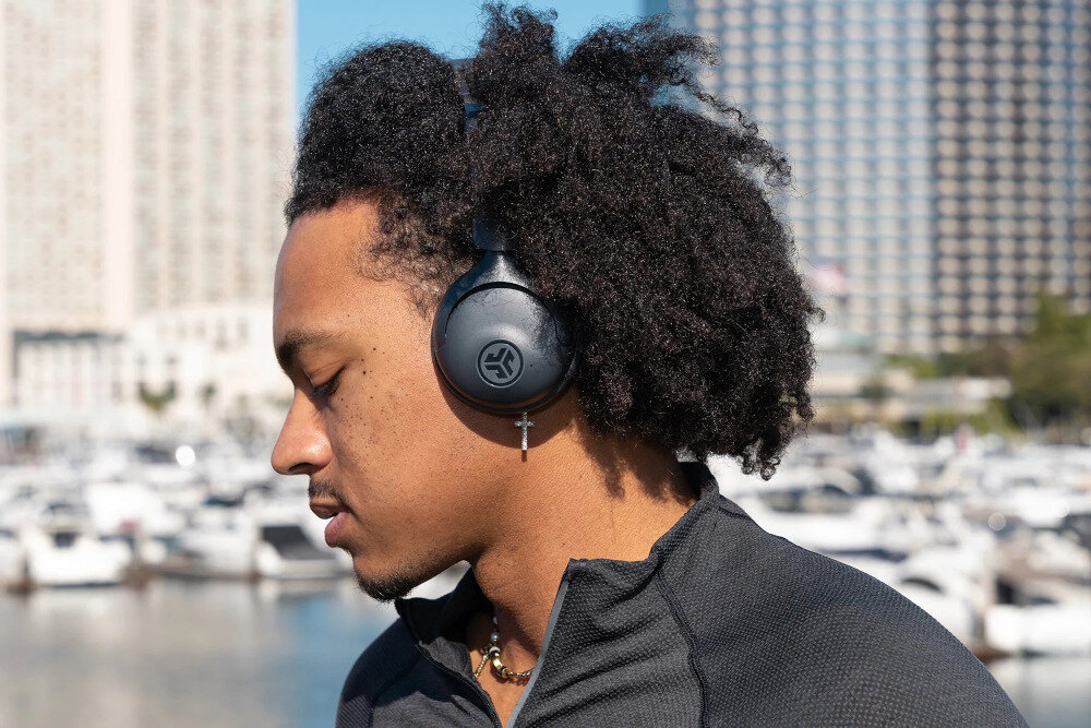 Słuchawki nauszne JLAB GO LUX ANC czas pracy do 70 h akumulator 600 mAh długa bateria, osoba z założonymi słuchawkami na głowie na świeżym powietrzu