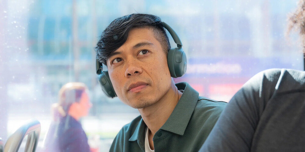 Słuchawki nauszne JLAB GO LUX ANC pasmo 20-20000 Hz dynamika 104 dB membrany dynamiczne szczegółowy dźwięk, osoba z założonymi słuchawkami na głowie na świeżym powietrzu