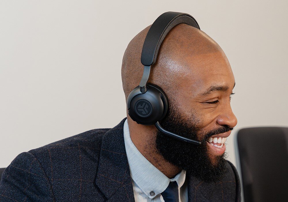 Słuchawki nauszne JLAB Epic Work, bezprzewodowe Bluetooth, komfort użytkowania, osoba z założonymi słuchawkami nausznymi uśmiechająca się