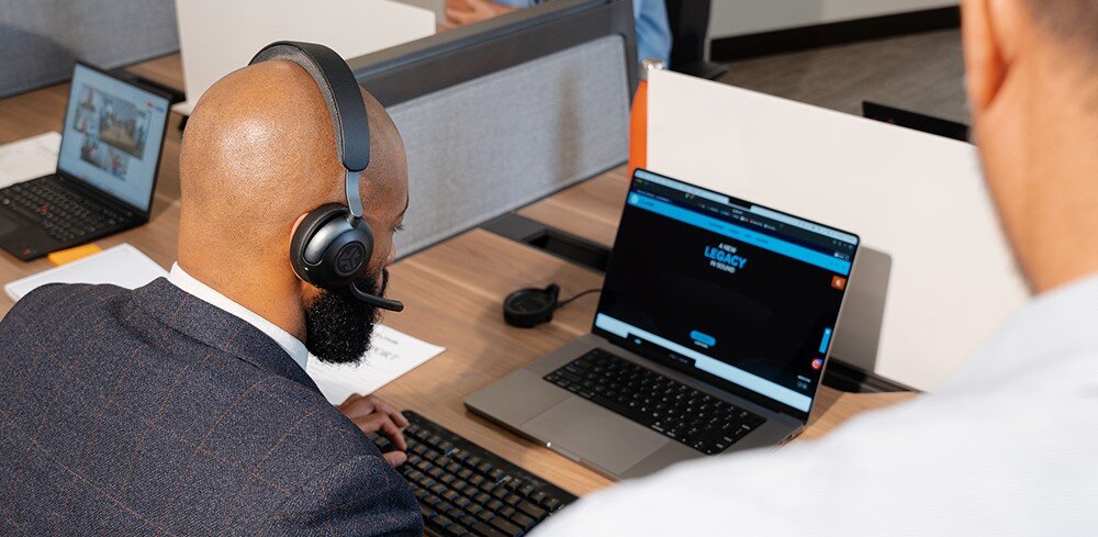 Słuchawki nauszne JLAB Epic Work, szybkie ładowanie USB-C, Quick Charge, osoba siedząca przy biurku z założonymi słuchawkami nausznymi