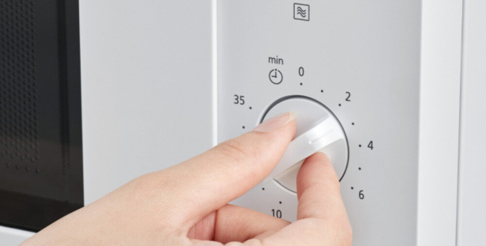 KUCHNIA MIKROFALOWA PANASONIC NN-SM21QWEPG Zbliżenie na panel sterowania białej kuchenki mikrofalowej, gdzie dłoń obraca pokrętło minutnika z wyraźną skalą czasu, podkreślając intuicyjną i prostą obsługę urządzenia prosta obsługa szybkie rozpoczęcie gotowania regulacja mocy ustawienie czasu minimalistyczny panel czytelne sterowanie wygodne pokrętła intuicyjna obsługa