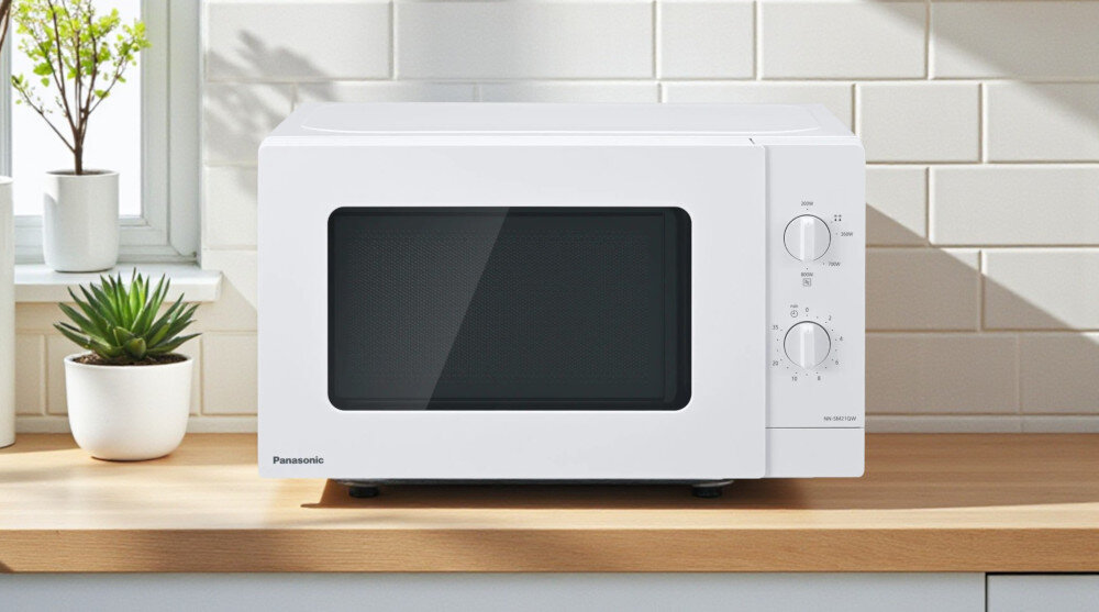 KUCHNIA MIKROFALOWA PANASONIC NN-SM21QWEPG Biała kuchenka mikrofalowa Panasonic stojąca na blacie w jasnej kuchni, na tle płytek i doniczek z roślinami, eksponuje swój prosty, minimalistyczny design, który łatwo wpasowuje się we wnętrza minimalistyczny design kuchnia zaokrąglone krawędzie czytelne pokrętła matowe wykończenie drzwi estetyczny wygląd codzienny komfort