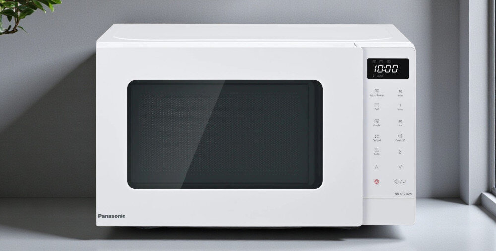 KUCHNIA MIKROFALOWA PANASONIC NN-GT21QWEPG Biała kuchenna kuchenka mikrofalowa Panasonic ustawiona na blacie przy oknie, z dużymi czarnymi drzwiczkami, cyfrowym wyświetlaczem 10:00 i panelem dotykowym po prawej stronie prosty i elegancki design stylowa kuchnia zaokrąglone krawędzie wyświetlacz LED białe podświetlenie panel dotykowy matowe wykończenie drzwi estetyczne wykonanie codzienna wygoda komfort użytkowania