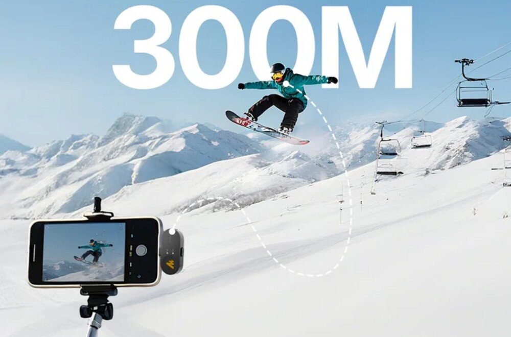 Osoba na snowboardzie skacze nad śnieżnym stokiem, a w tle widać wyciągi narciarskie. Na pierwszym planie znajduje się smartfon na statywie, na ekranie którego widoczna jest ta sama scena, a nad nią duży napis \'300M\'.