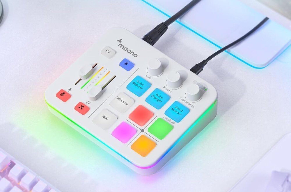 Kontroler do produkcji muzycznej i podcastów MAONO G1 Neo biały mikser audio widziany z góry pod kątem, z podpiętym kablem xlr oraz przewodem usb, leżący na jasnym blacie obok fragmentu białej klawiatury mechanicznej