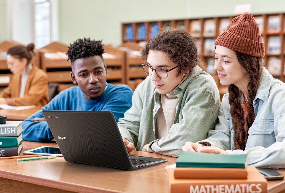 Laptop ACER Chromebook 514 C937-TCO-C9MW Troje młodych ludzi siedzi w bibliotece przy stole, wspólnie korzystają z laptopa ustawionego przed nimi, kamera, mikrofony, zabezpieczenia, audio