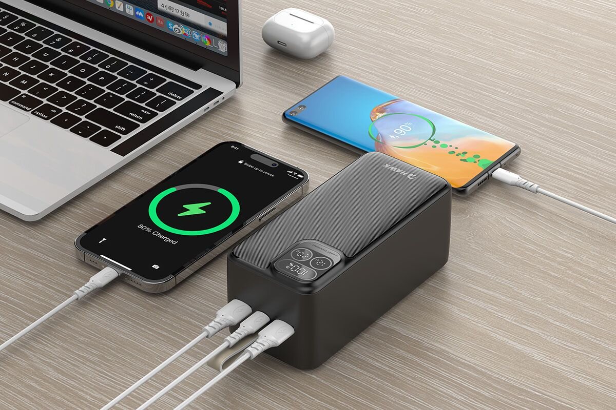 HAWK HW-PB50000 Dwa porty USB-A jedno złącze USB-C wejście i wyjście ładowanie do trzech urządzeń jednocześnie pełna moc portu zrównoważony do 15 W - trzy przewody podłączone do powerbankas, obok dwa ładujące się telefony