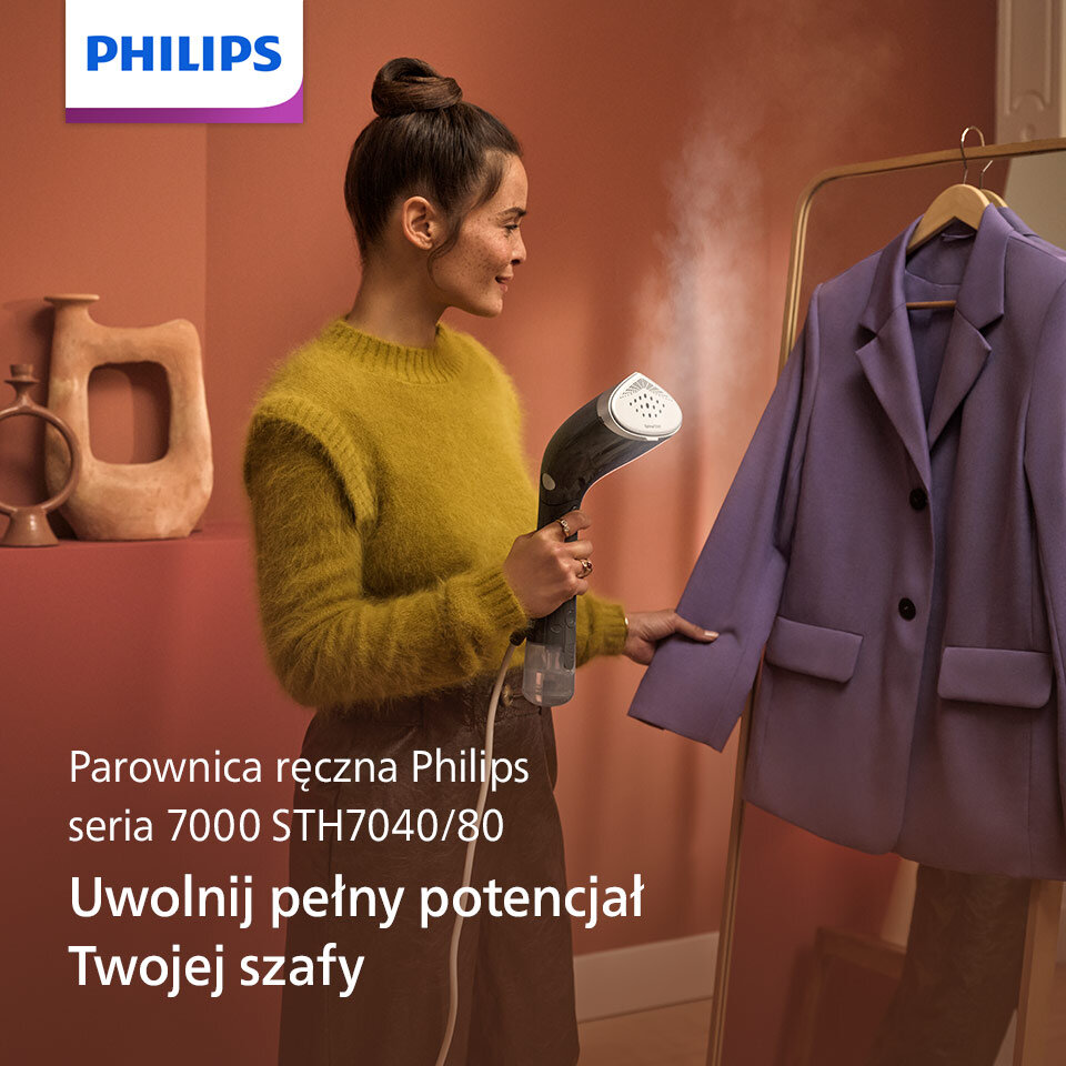 Osoba używa parownicy do ubrań, kierując parę na fioletową marynarkę wiszącą na wieszaku. Widoczny tekst: \'Parownica ręczna Philips seria 7000 STH7040/80 Uwolnij pełny potencjał Twojej szafy\'.