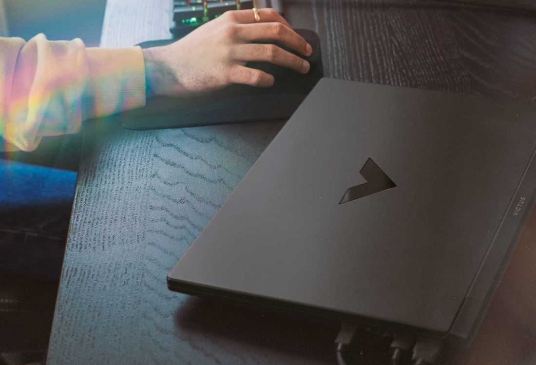 Laptop HP Victus 15 - Osoba korzystająca z laptopa, na którym widoczne jest logo HP Victus. Wi-Fi 6 Bluetooth 5.3
