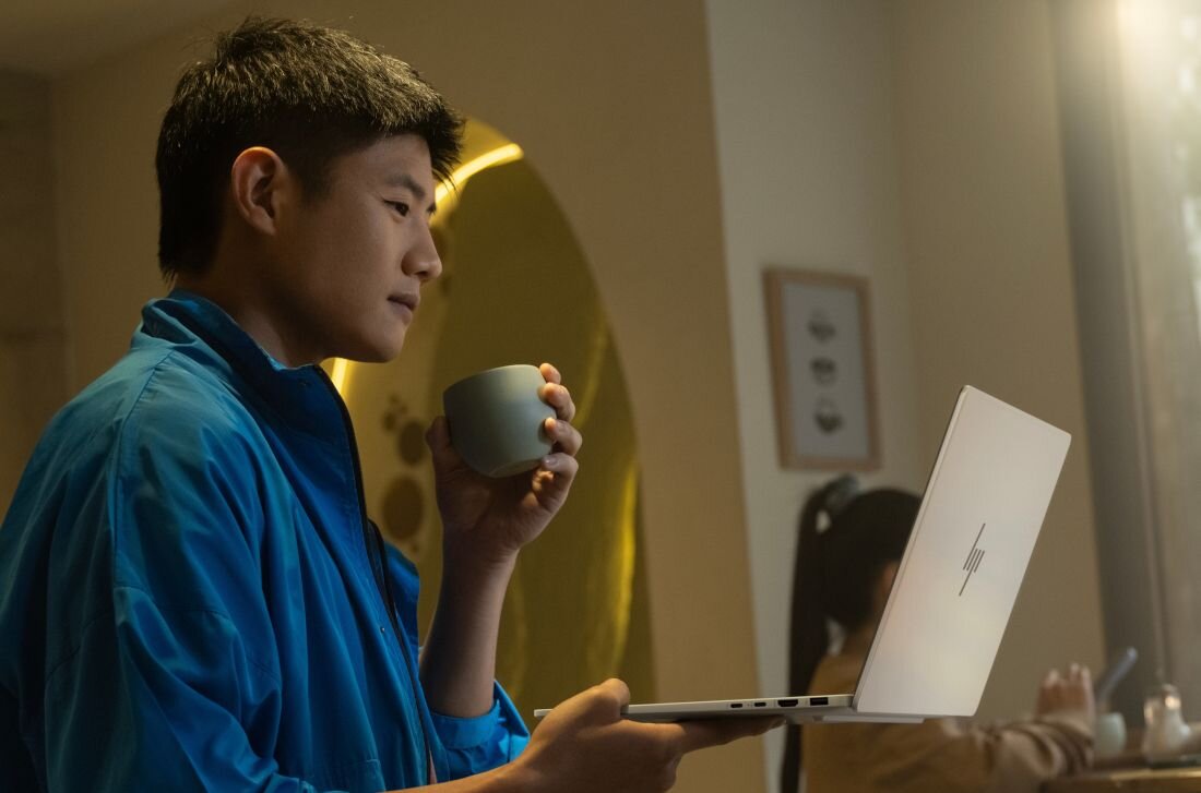 Mężczyzna w niebieskiej koszuli pracujący na laptopie HP OmniBook Aero z kubkiem kawy w wieczornym oświetleniu. - Wytrzymałość, Testowanie MIL-STD 