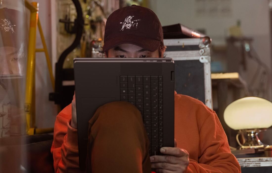 Użytkownik z laptopem HP OmniBook w trybie tabletu, scena w warsztacie z pomarańczowym światłem. - EPEAT Gold z Climate+ ENERGY STAR