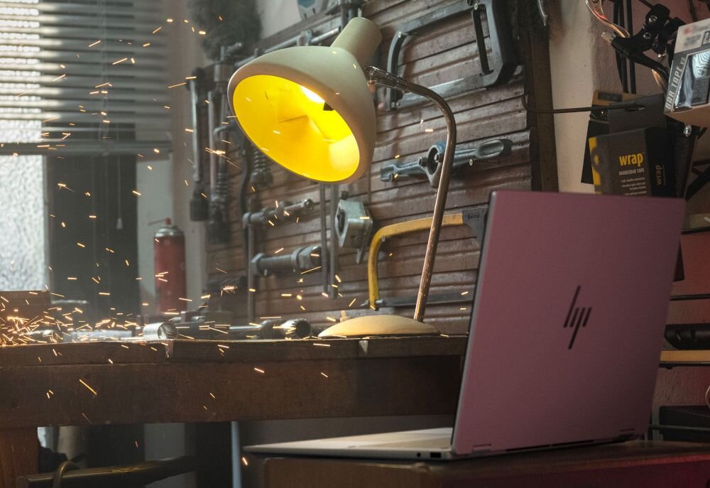 Laptop HP OmniBook na biurku warsztatowym obok lampy, podczas pracy generującej iskry. - dysk SSD PCIe Gen4 NVMe M.2