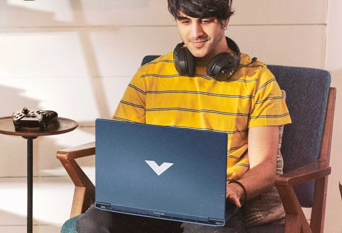 Laptop HP Victus 15 - Mężczyzna w słuchawkach siedzi na krześle, używając laptopa do pracy. Pamięć DDR5, Dysk SSD PCIe NVMe