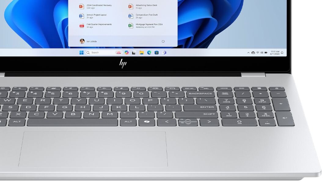 Klawiatura laptopa HP OmniBook z czarnymi klawiszami i dużym touchpadem na tle lasu z zielonymi liśćmi. - podświetlana klawiatura z białym podświetleniem LED