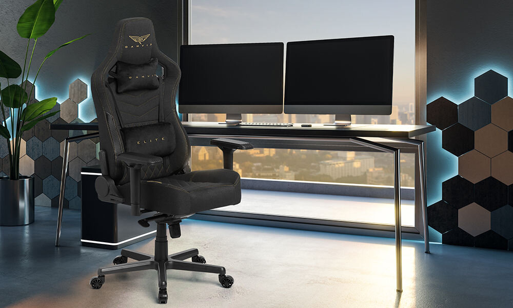 Fotel GAMVIS Elite 2.0 Pro XL Tkanina Czarny (złote elementy) prezentacja fotela w pokoju przy biurku dwa monitory stojące na biurku za nim duże okno na ścianie panele geometryczne z podświetleniem wielozadaniowość fotel biurowy gamingowy komfort