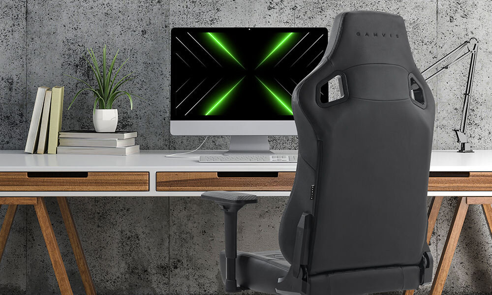 Fotel GAMVIS Elite 2.0 Pro XXL Czarny prezentacja fotela w pokoju przy biurku na nim monitor obok kwiatki lampka brązowy blat biurka płaskie siedzisko ZeroStress+ mechanizm bujania MultiLockSpec+ wygoda