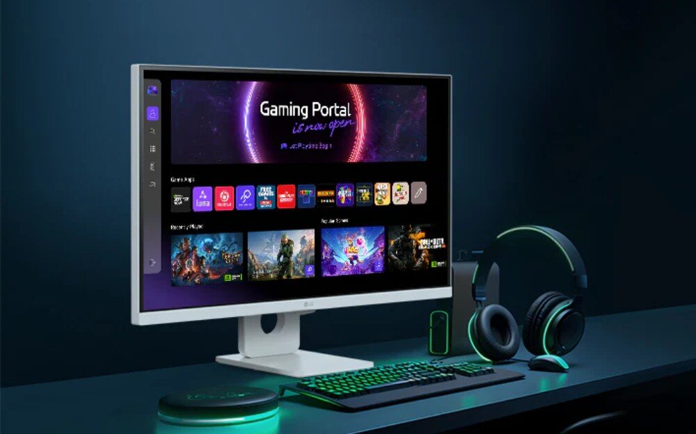 Monitor LG Smart 27U731SA-W.AEU Monitor stojący na ciemnym biurku dla gracza z uruchomionym panelem Gaming Portal, obok którego leżą czarne słuchawki, myszka oraz klawiatura z zielonym podświetleniem, czas reakcji, odświeżanie, granie