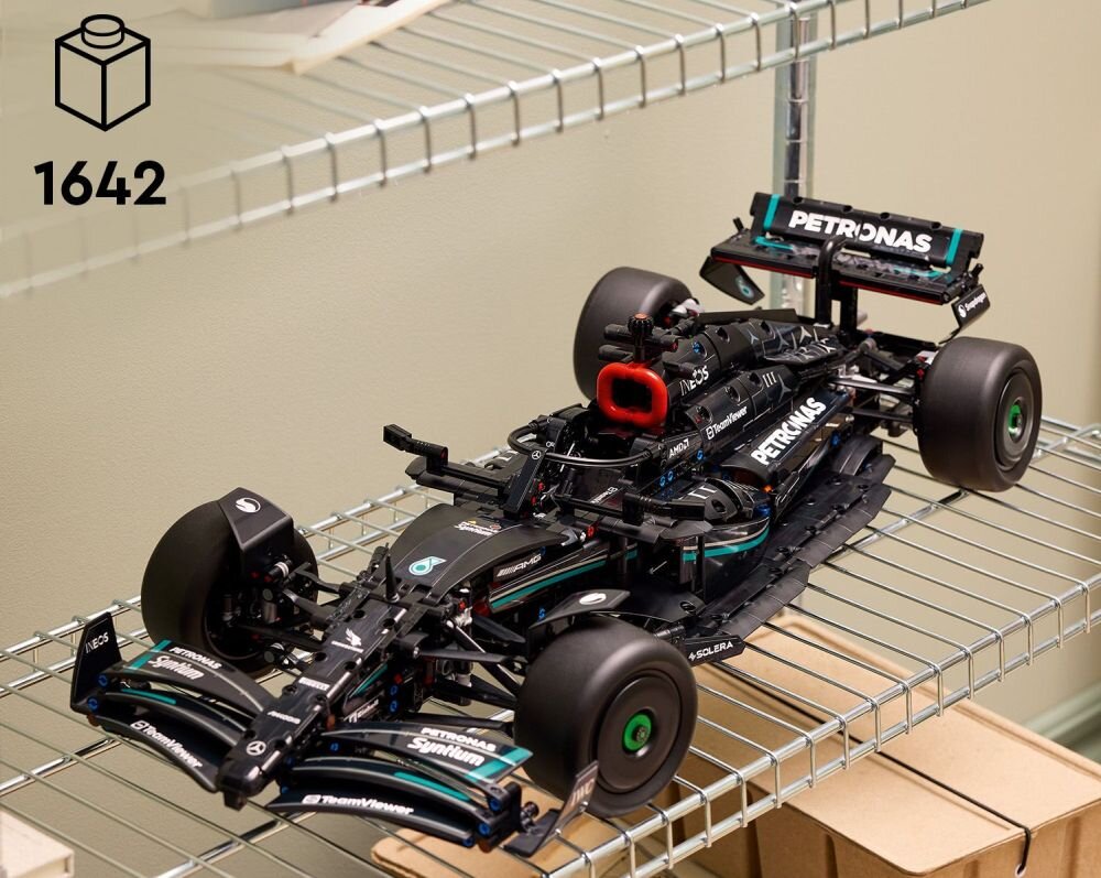 Model samochodu wyścigowego z klocków LEGO umieszczony na metalowej półce. Na samochodzie widoczne są napisy \'PETRONAS\' oraz \'INEOS\'.