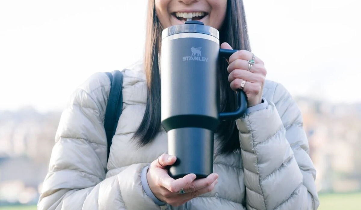 Kubek termiczny STANLEY Quencher H2.0 FlowState Tumbler trzymany w ręce przez uśmiechniętą osobę