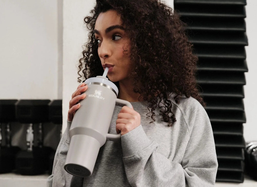 Kubek termiczny STANLEY Quencher H2.0 FlowState Tumbler trzymany w ręce przez uśmiechniętą osobę