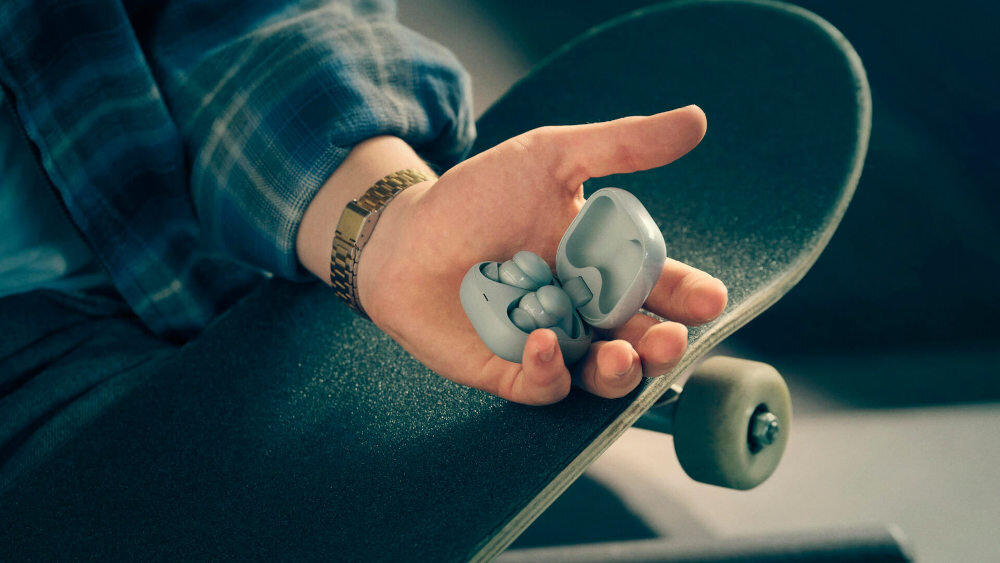 Słuchawki dokanałowe SONY LinkBuds WF-LS910 komfort na cały dzień 4,9 g Air Fitting IPX4, osoba trzymająca słuchawki z etui ładującym w ręku opartej na deskorolce