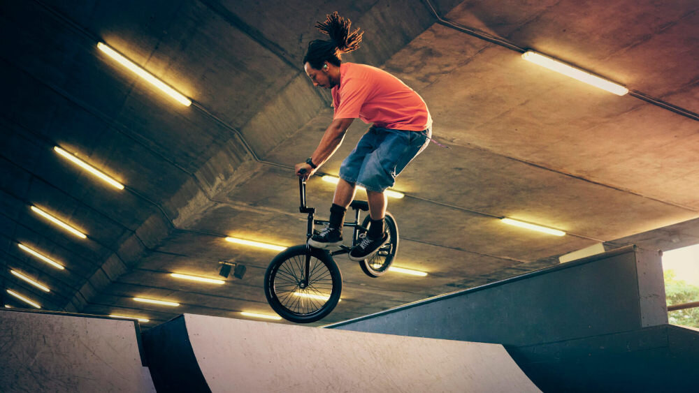 Słuchawki dokanałowe SONY LinkBuds WF-LS910 Hi-Res Audio Wireless DSEE Extreme jakość brzmienia, osoba z założonymi słuchawkami, skacząca na rampie na rowerze