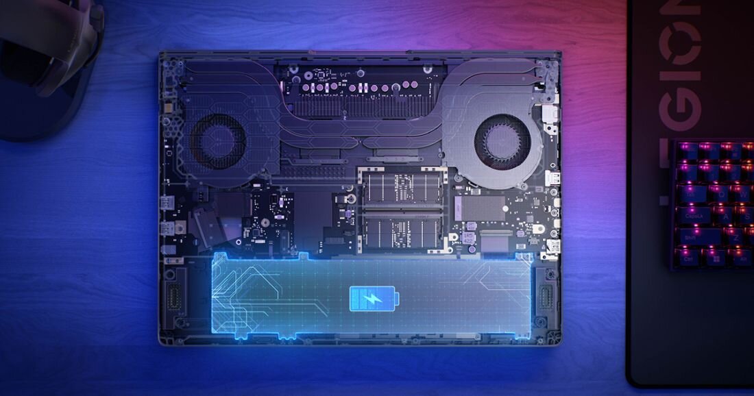  Widok z góry wnętrza laptopa Lenovo Legion z przezroczystą technologiczną nakładką pokazującą ikonę baterii turkusowo-niebieską z diagramem cyfrowym obwodów, dwa wentylatory chłodzenia czarne okrągłe, centralny radiator metalowy, moduły RAM DDR5 czarne, płyta główna z czarnymi komponentami, niebieski gradient podświetlenia, klawiatura RGB wielokolorowa po prawej stronie z napisem Legion, tło niebiesko-fioletowe. - Bateria 80 Wh 