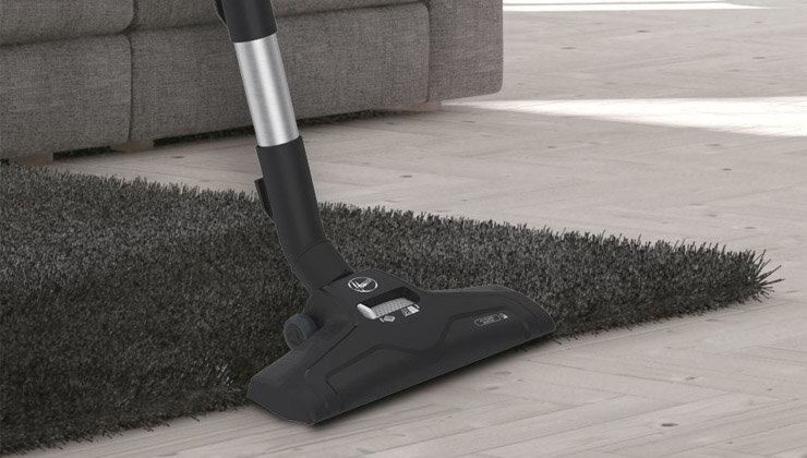 Na obrazie widoczna jest czarna głowica odkurzacza na ciemnym dywanie, z logo \'Hoover\' i napisem \'media expert\'.