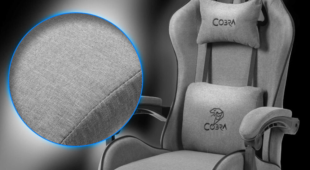 Szary fotel gamingowy z poduszkami, na których widnieje logo \'COBRA\'. Zbliżenie na teksturę materiału obicia fotela.