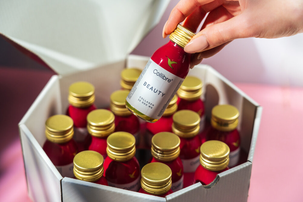 Kolagen COLLIBRE Beauty shot 15 x 60 ml osoba wyciąga jedną buteleczkę z pudełka zestaw 15 buteleczek z kolagenem pojemność 60 ml każda