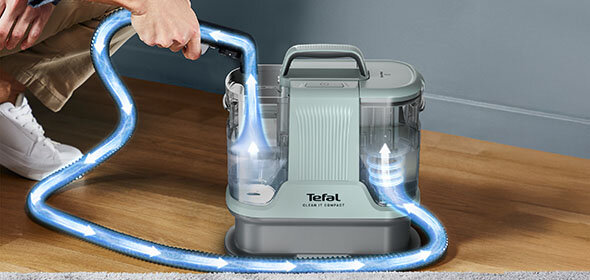 Niebieska wiązka i strzałki pokazują przepływ wody w odkurzaczu piorącym 2w1 Clean It IZ3020, który stoi na podłodze.