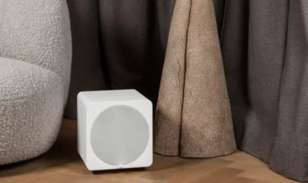 Subwoofer VELODYNE MicroVee X 6.5 kompaktowy rozmiar 30x29x29 cm, subwoofer stojący na podłodze obok kanapy