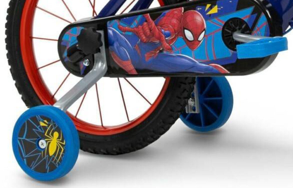 Fragment roweru dziecięcego z grafiką Spider-Mana na osłonie łańcucha. Koła pomocnicze mają niebieskie obręcze z żółtym symbolem pająka.