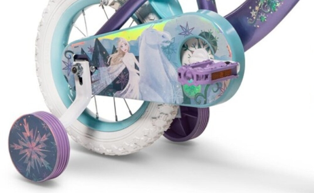 Rower dziecięcy HUFFY Disney Kraina Lodu 12 cali Fioletowo-niebieski Wzrost: 85-100 cm Wiek: 3-5 lat  zbliżenie na kółka boczne i osłonę łańcucha zdjęcie na białym tle boczne kółka asekurują dziecko w początkowej fazie nauki boczne kółka można łatwo usunąć osłona łańcucha kolorowa grafika z wizerunkami Anny Elsy i Olafa zabezpiecza łańcuch przed brudem