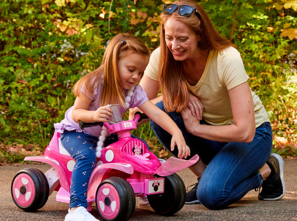 Quad elektryczny dla dziecka HUFFY Minnie Mini 19075W Ciemnoróżowy park dziecko siedzi na pojeździe otwiera schowek obok dorosła osoba uśmiechnięte buzie w tle drzewa droga urocze grafiki Minnie dopracowane elementy nadwozia cokół siedzenia praktyczny przedni schowek na drobiazgi