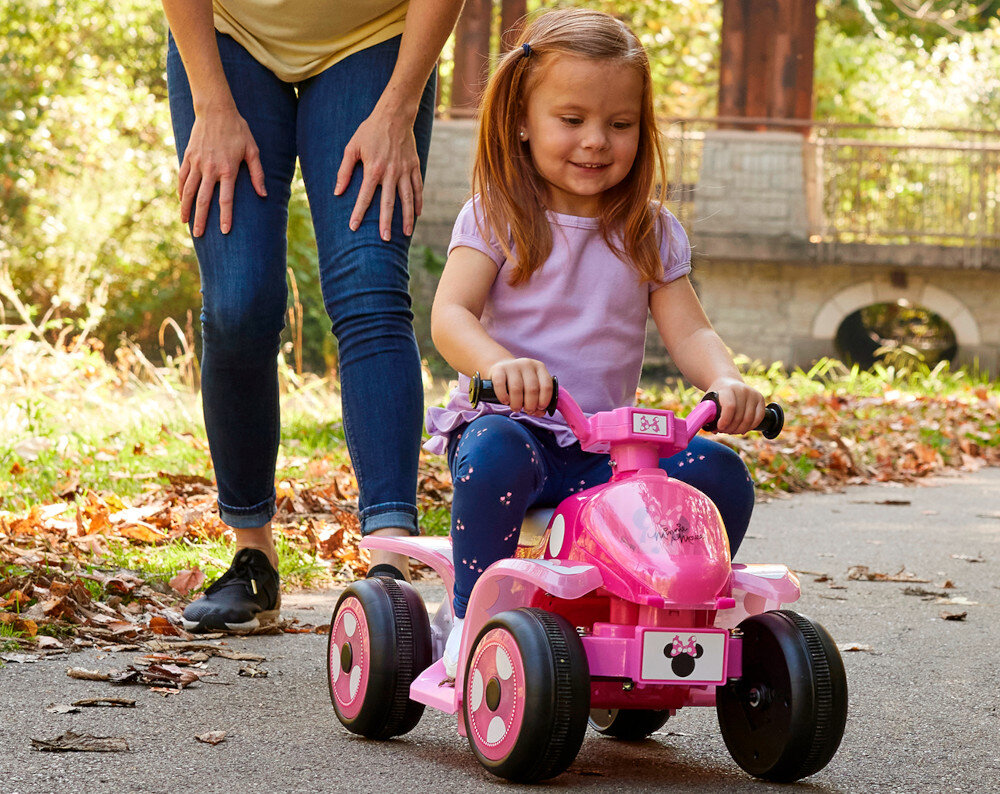 Quad elektryczny dla dziecka HUFFY Minnie Mini 19075W Ciemnoróżowy park dziecko jedzie na pojeździe w tle dorosła osoba uśmiechnięte buzie w tle drzewa droga zasilanie akumulator litowo-jonowy 7,2 V czas działania do 40 minut czas ładowania do 12 godzin