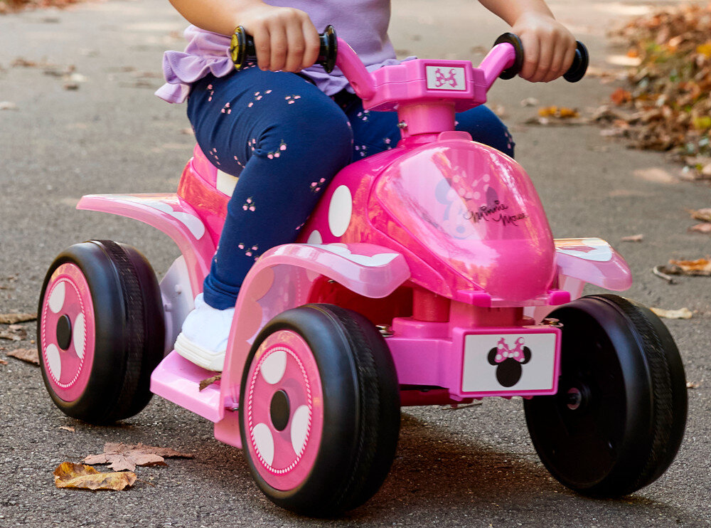 Quad elektryczny dla dziecka HUFFY Minnie Mini 19075W Ciemnoróżowy park zbliżenie na pojazd na pojeździe siedzi dziecko w tle droga liście dla dzieci w wieku od 1,5 do 3 lat o maksymalnej wadze do 20 kg bezpieczny stabilny postać myszki Minnie