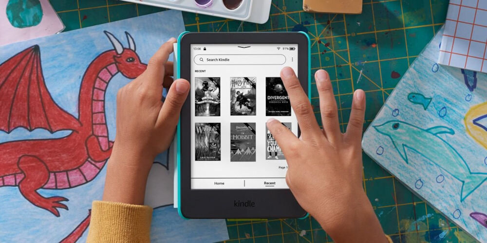 Czytnik e-booków AMAZON Kindle Kids Space Whale 6 cali, Podświetlany ekran, Wi-Fi, Bez reklam Dziecko trzyma Kindle Kids nad kolorowym rysunkiem smoka i delfina, na biurku leżą przybory plastyczne 16 GB pamięci Wi-Fi subskrypcja Amazon Kids+ przenośna biblioteka dostęp do szerokiego katalogu książek